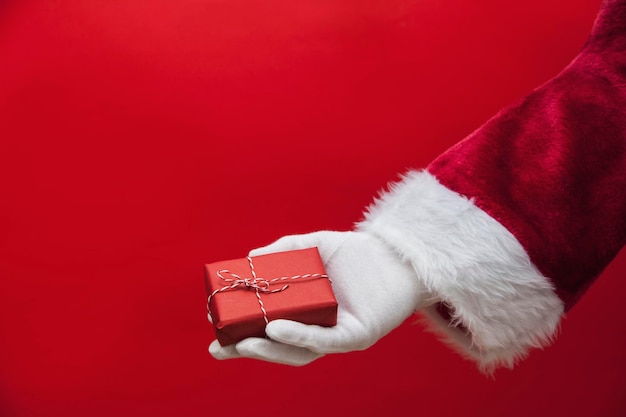 Mano de Santa Claus sosteniendo un regalo de Navidad