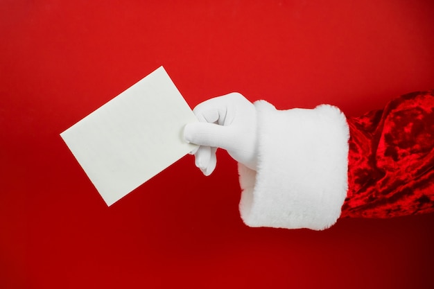 Mano de Santa Claus sosteniendo una tarjeta de Navidad vacía.