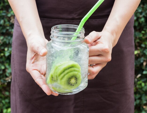 Mano en servir vaso de bebida helada de kiwi soda