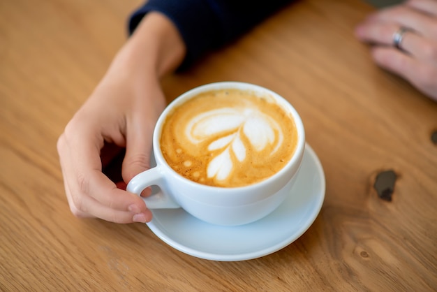 Mano sobre la mesa una taza de café