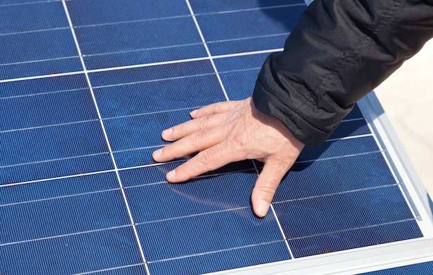 Mano sobre panel solar