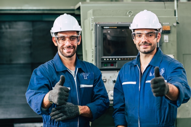 La mano sonriente del equipo feliz del trabajador muestra el pulgar para arriba para el buen trabajo en fábrica.