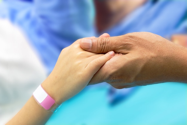 Foto mano sostenga la mano de un paciente infantil con pulsera