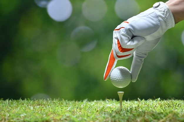 Mano sostenga la pelota de golf con tee en el campo de golf