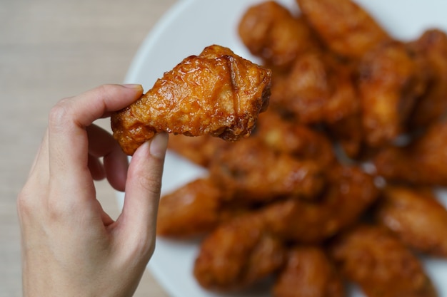 Mano sosteniendo alitas de pollo fritas picantes