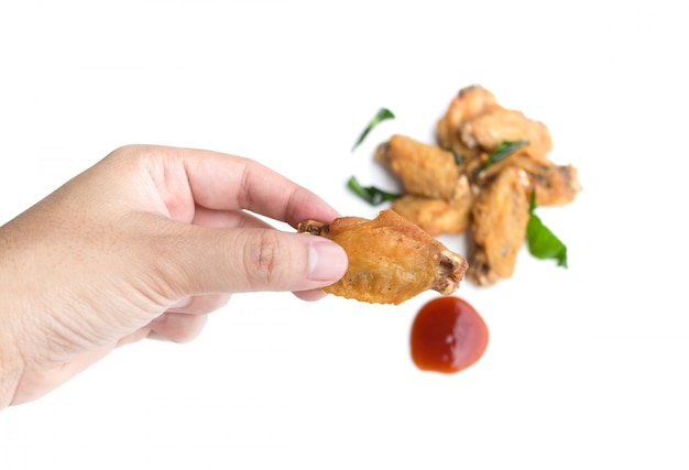 Mano sosteniendo alitas de pollo fritas y salsa de tomate aislado en blanco