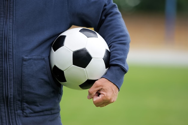 Foto mano sosteniendo un balón de fútbol en el estadio