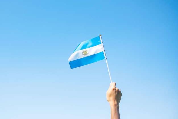 Mano sosteniendo la bandera argentina en el fondo de la naturaleza 9 de julio del Día de la Independencia 25 de mayo del Día de la Revolución y conceptos de celebración feliz