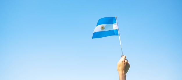Mano sosteniendo la bandera argentina en el fondo de la naturaleza 9 de julio del día de la independencia 25 de mayo del día de la revolución y conceptos de celebración feliz