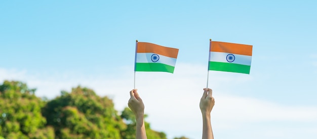 Foto mano sosteniendo la bandera de la india sobre fondo de cielo azul. vacaciones del día de la república de la india, feliz día de la independencia y conceptos de gandhi jayanti