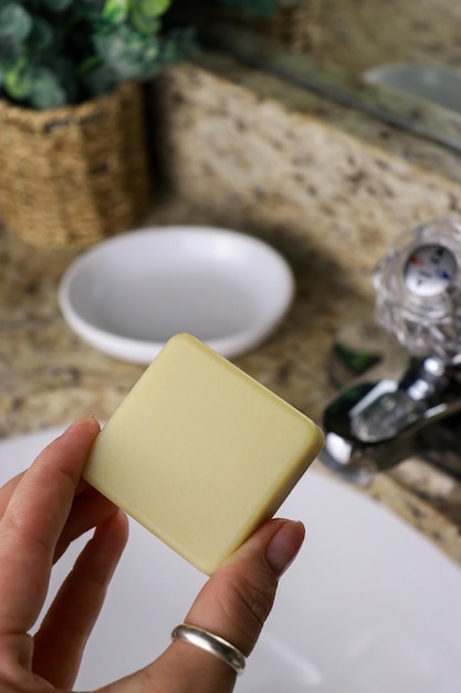 mano sosteniendo una barra de jabón sin residuos, lavabo del baño