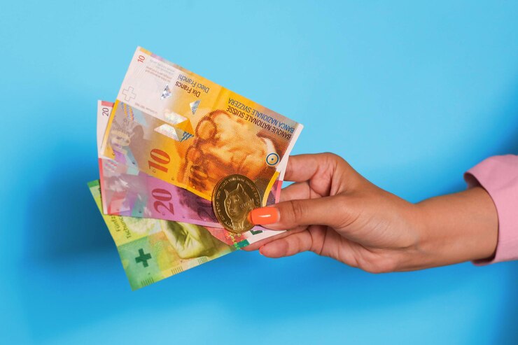 Mano sosteniendo billetes de corona sueca y moneda criptográfica sobre fondo azul