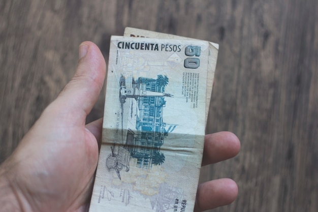 Foto mano sosteniendo billetes de dinero argentino. dinero argentino.