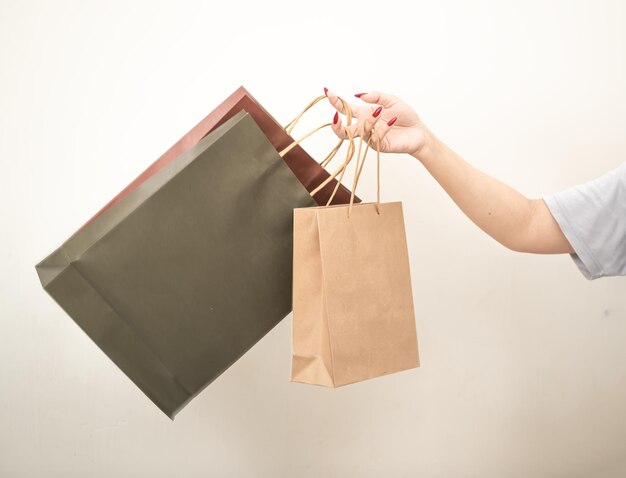 Foto mano sosteniendo una bolsa de papel de compras contra un fondo aislado blanco