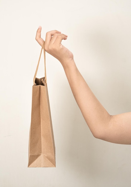 Foto mano sosteniendo una bolsa de papel de compras contra un fondo aislado blanco