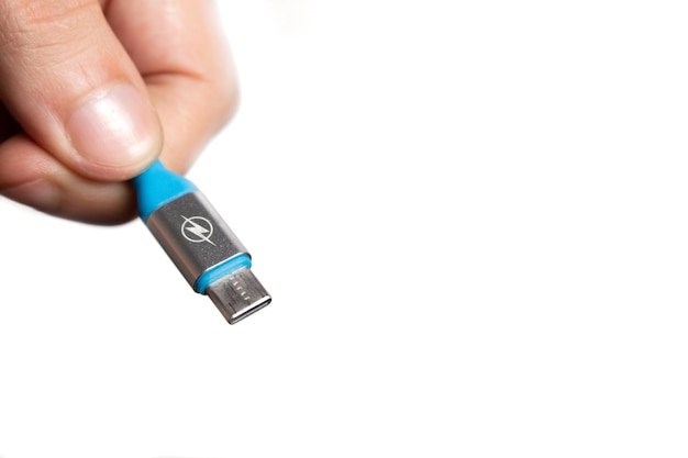 Mano sosteniendo un cable USB C azul sobre fondo blanco.