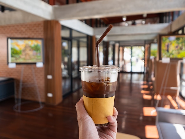 Mano sosteniendo café helado en café