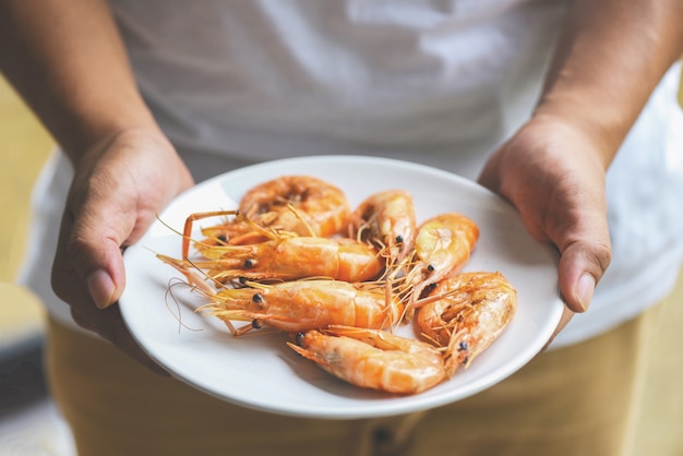 Mano sosteniendo camarones a la plancha gambas cocidas