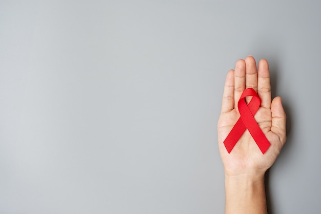 Mano sosteniendo la cinta roja para el día mundial del sida