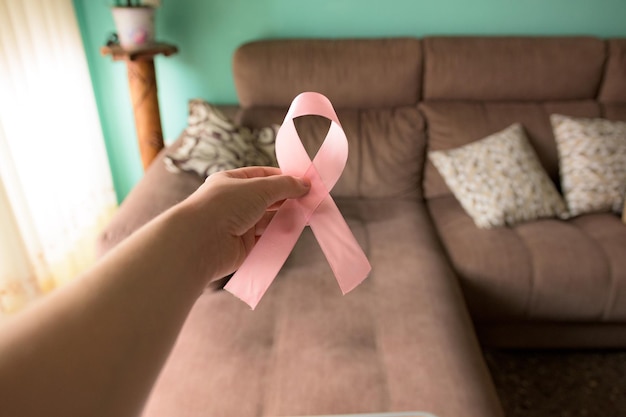 Mano sosteniendo una cinta rosa de concientización sobre el cáncer