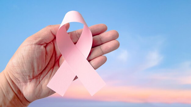 La mano sosteniendo una cinta rosa que simboliza el cáncer de mama para aumentar la conciencia de la gente