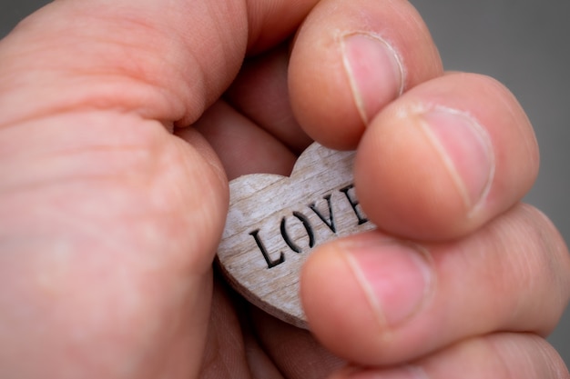 Foto mano sosteniendo un corazón de madera con las letras amor signo de amor en tu mano