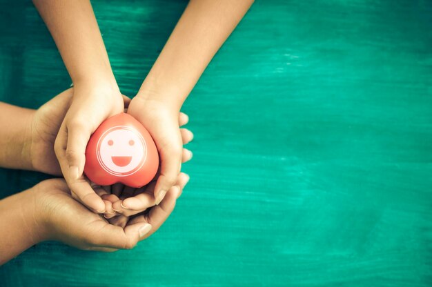 Una mano sosteniendo un corazón rojo con una ola de corazón. Ella lo sostiene con la mano sobre un fondo azul. Salud del corazón. Caridad voluntaria feliz. La foto muestra el principio del cuidado y la buena salud.