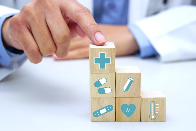 Foto mano sosteniendo un cubo de bloque de madera con símbolo de icono médico sanitario. concepto médico y de salud.