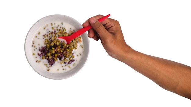 La mano sosteniendo una cuchara de avena de frijol verde en un fondo blanco aislado