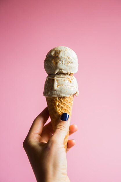 Una mano sosteniendo dos bolas de helado de vainilla