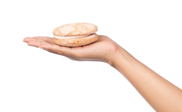 mano sosteniendo galletas de crema de vainilla aisladas sobre fondo blanco.