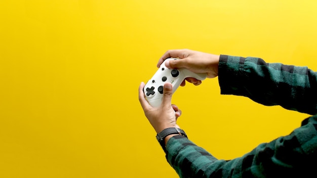 Mano sosteniendo un gamepad o joystick contra un fondo amarillo