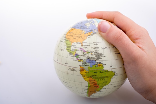 La mano sosteniendo un globo con el mapa en él