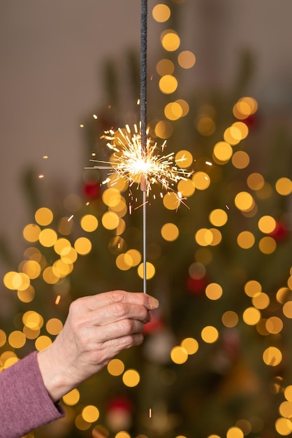 Mano, sosteniendo hermosas luces brillantes o bengalas. Feliz navidad y año nuevo concepto.