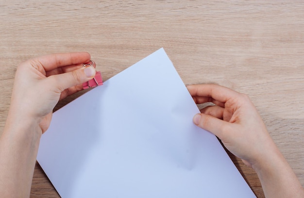 Mano sosteniendo hojas de papel sobre un fondo de madera