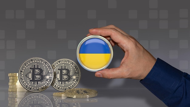 Una mano sosteniendo una insignia con la bandera ucraniana frente a algunos bitcoins. Concepto de moneda criptográfica.