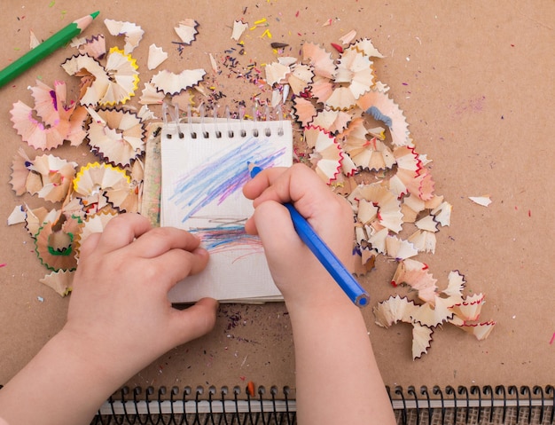 Foto la mano sosteniendo un lápiz de color en cuadernos en espiral con basura de lápiz