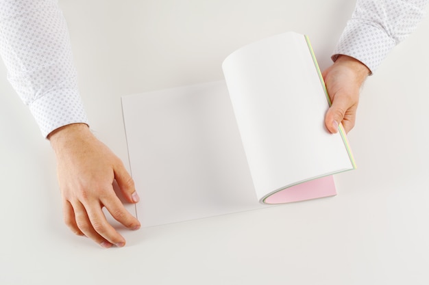 Foto mano sosteniendo el libro abierto en blanco simulacro