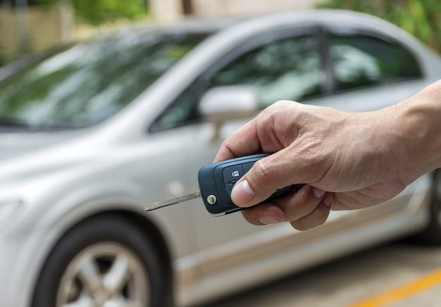 Mano sosteniendo las llaves sobre foto borrosa de coche usado para abrir