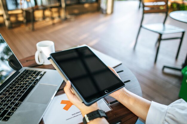 La mano sosteniendo una mesa con una computadora portátil en la cafetería