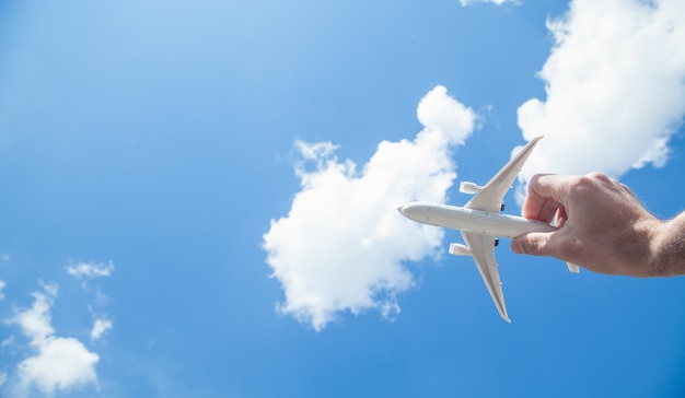 Mano sosteniendo el modelo de avión frente a fondo de cielo azul. Viajar