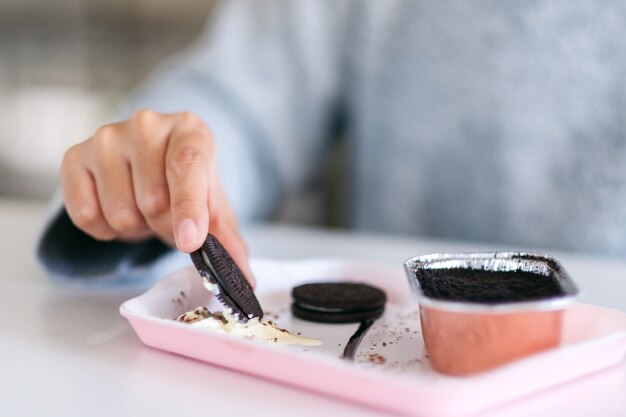 Foto una mano sosteniendo y mojando una galleta de chocolate en crema batida