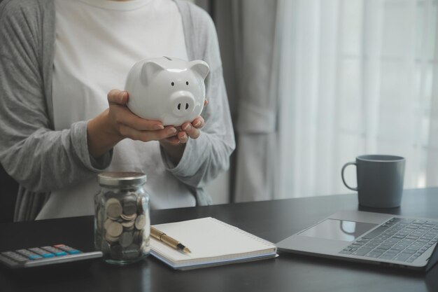 Mano sosteniendo moneda con hucha de cerdo Concepto de ahorro y cuentas financieras