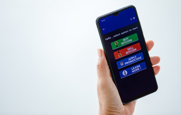 Mano sosteniendo y mostrando la pantalla del teléfono inteligente con botones de código de compra y venta y promoción en la aplicación de comercio de criptomonedas con espacio de copia.
