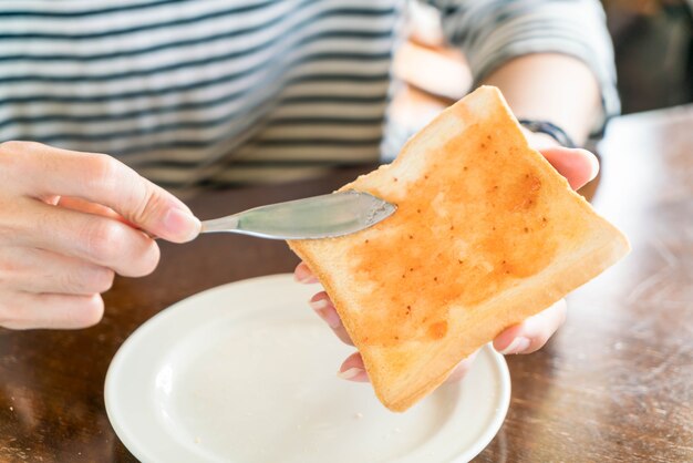 Mano sosteniendo pan y mermelada de fresa para el desayuno