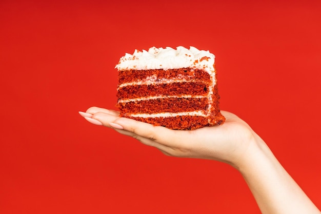 Mano sosteniendo un pastel aislado sobre fondo rojo Closeup Copyspace