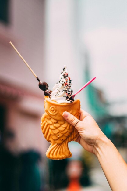 Foto una mano sosteniendo un pez naranja con una taza de café y helado