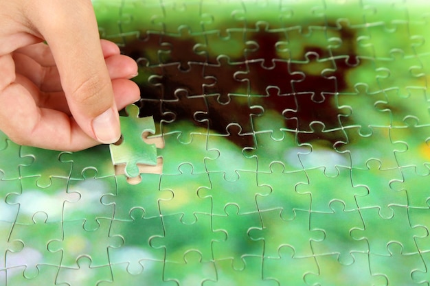 Foto mano sosteniendo la pieza del rompecabezas en el fondo de la mesa de madera