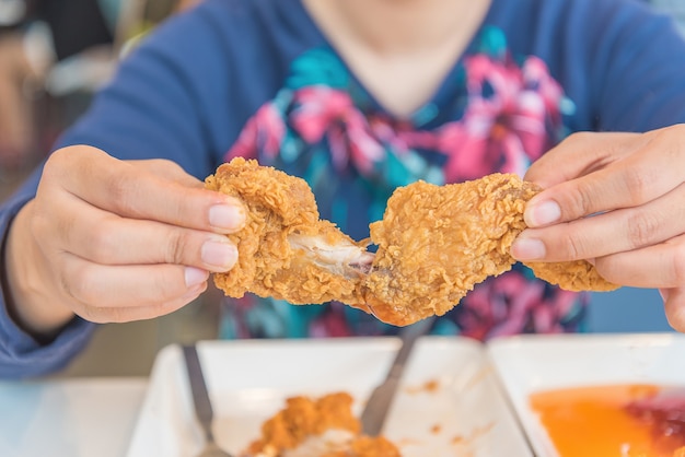 Foto mano sosteniendo pollo frito y comiendo en el restaurante