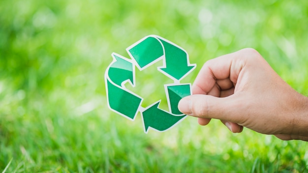 Foto mano sosteniendo reciclar símbolo contra la hierba verde